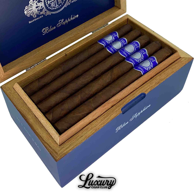 Close-up view of 1502 Blue Sapphire premium cigars with rich brown wrappers and vibrant blue bands, displayed in an elegant cedar-lined box by Luxury Cigar Club.