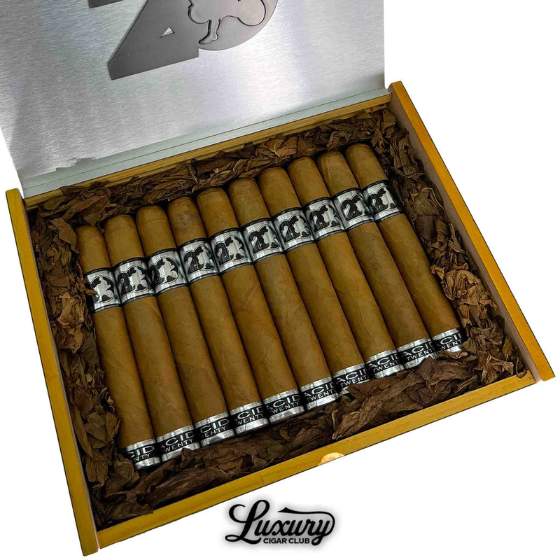 Close-up of open box of Acid 20 Connecticut Toro cigars, featuring light brown wrappers, silver and black bands, and surrounded by decorative tobacco leaves, with Luxury Cigar Club logo at the bottom.