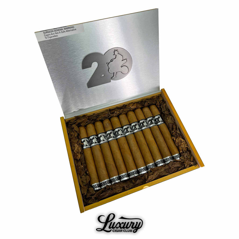 Open box of Acid 20 Connecticut Toro cigars with silver lid displaying "20" and silhouette logo, surrounded by tobacco leaf padding, and Luxury Cigar Club logo below.