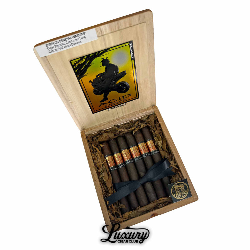 Open box of Acid Subculture Toast cigars with dark brown wrappers and orange-brown holographic bands, packaged with tobacco leaf lining, Luxury Cigar Club logo