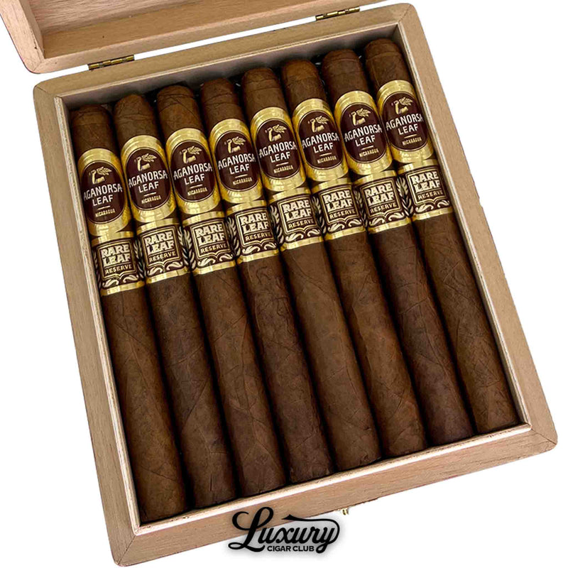Close-up view of Aganorsa Leaf Rare Leaf Reserve Corojo Lonsdale cigars inside the box, showcasing dark brown wrappers with gold and maroon bands reading “Aganorsa Leaf Nicaragua” and “Rare Leaf Reserve.” Luxury Cigar Club.