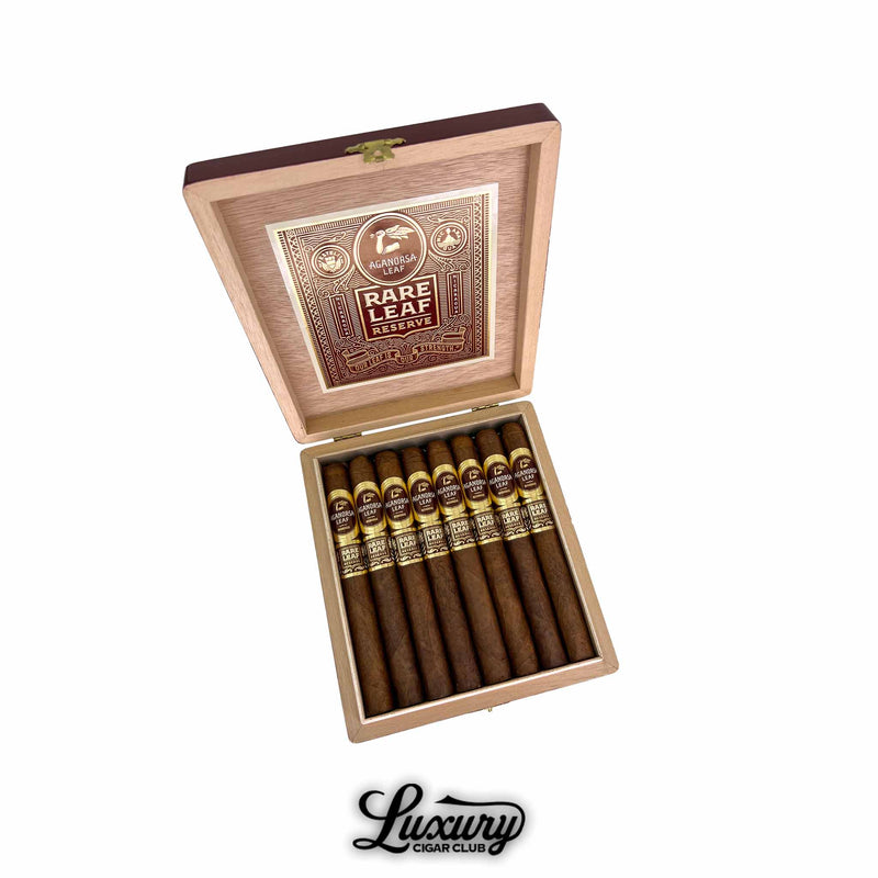 Open wooden box of Aganorsa Leaf Rare Leaf Reserve Corojo Lonsdale cigars, featuring elegant brown and gold bands and the signature Aganorsa Leaf logo inside the lid. Luxury Cigar Club branding below.