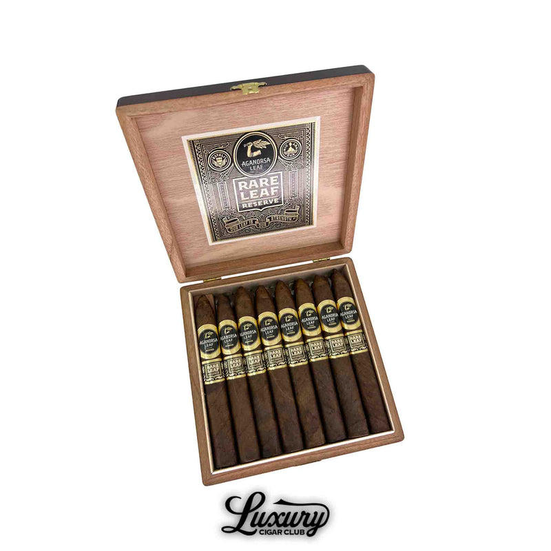 Open wooden box of Aganorsa Leaf Rare Leaf Reserve Maduro Torpedo cigars, showcasing rich dark brown wrappers with black and gold dual bands and the Aganorsa Leaf logo inside the lid. Luxury Cigar Club branding below.