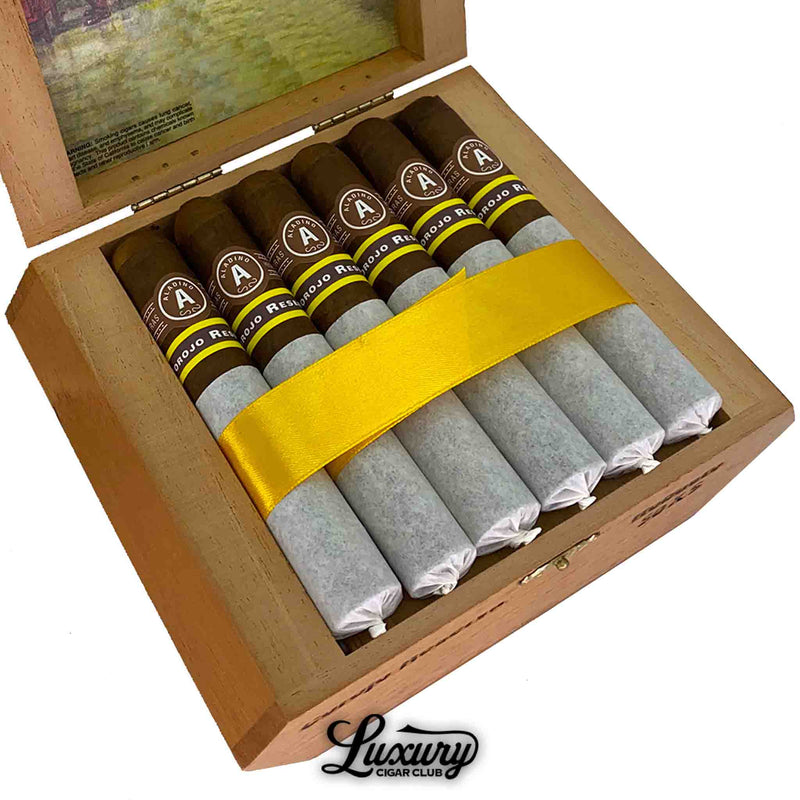 Detailed close-up of Aladino Corojo Reserva Robusto cigars in box, covered with tissue and gold band, high-end cigars online.