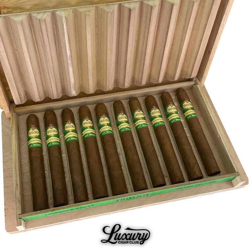 Close-up of Alec Bradley Trilogy Authentic Corojo Limited Edition Toro cigars in a natural wood box, highlighting the green and gold bands and unique triangular box-pressed shape.