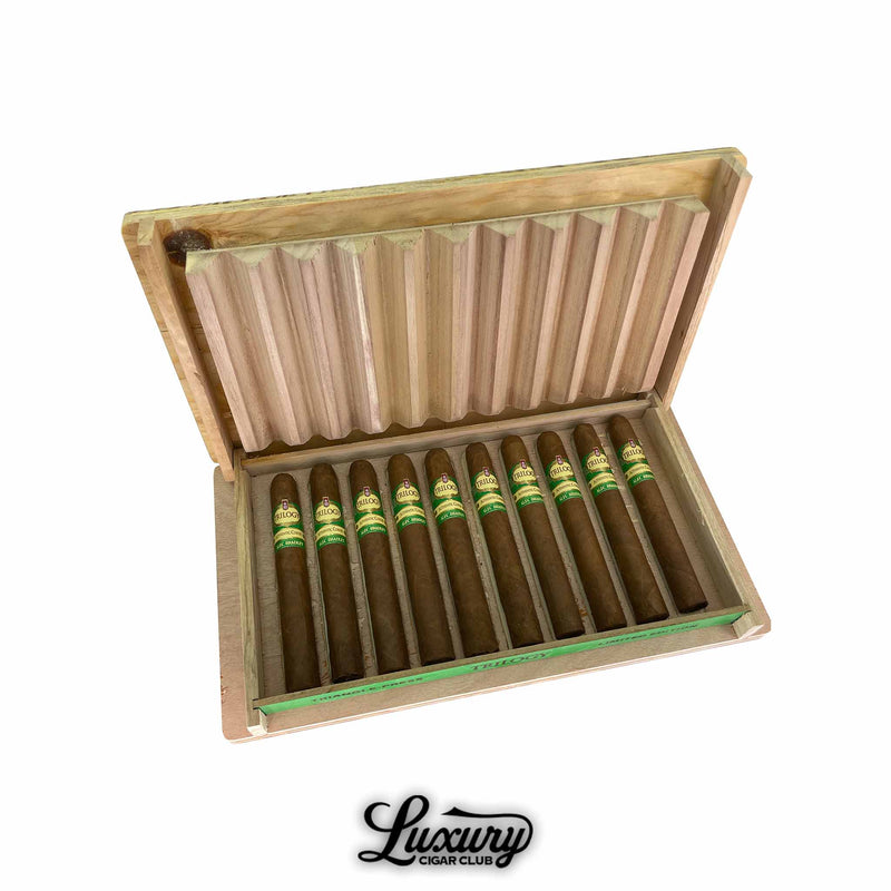 Open box of Alec Bradley Trilogy Authentic Corojo Limited Edition Toro cigars displayed in a wooden crate with corrugated lid, featuring cigars banded in green and gold with "Trilogy" branding.