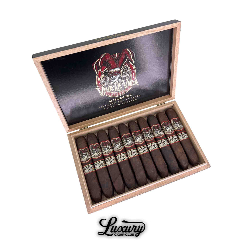 Open box of Artesano Del Tobacco Viva La Vida 5th Anniversary Club 500 Sabroso cigars, presented in a wood box with the jester logo on the lid and ten dark-wrapped cigars featuring gold and red Club 500 bands, handcrafted by AJ Fernandez in Estelí, Nicaragua.