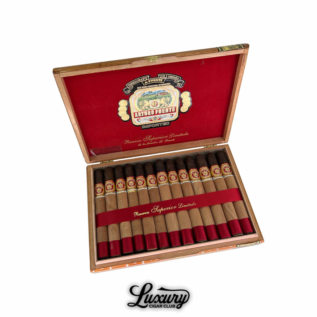 Open box of Arturo Fuente Anejo Maduro Limited Edition No 60 cigars with red ribbon and cedar sleeves, available at Luxury Cigar Club.