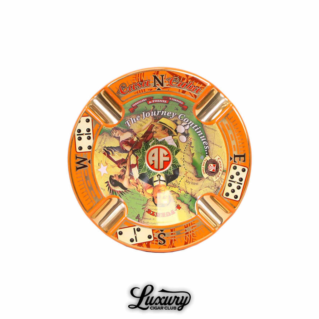 Arturo Fuente Casa Cuba limited edition porcelain ashtray featuring a vibrant orange rim, gold cigar rests, compass markings, domino illustrations, and central artwork with "The Journey Continues" text and AF logo.