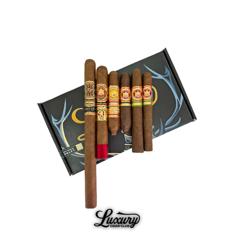 Arturo Fuente Don Carlos 90th Dos Capas cigar sampler from Luxury Cigar Club featuring six premium cigars including Fuente Fuente OpusX Lost City Hemingway and Casa Cuba displayed over a black and gold presentation box.