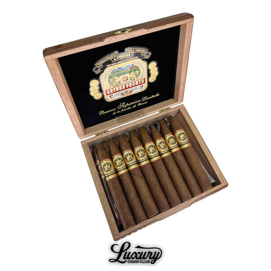 Open box of Arturo Fuente Don Carlos No. 2 cigars, featuring 8 torpedo-shaped dark brown cigars with elegant gold, black, and red bands. The inner lid displays a colorful Arturo Fuente logo and “Reserva Superior Limitada” text, with “Luxury Cigar Club” branding at the bottom.