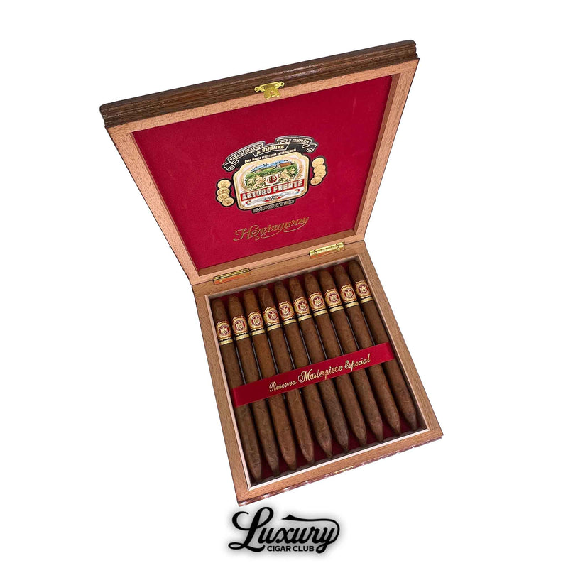 Open wooden box of Arturo Fuente Hemingway Natural Masterpiece cigars with red velvet interior and gold detailing, showing 10 premium torpedo cigars inside.