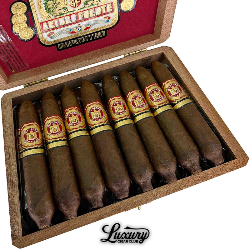 Close-up of Arturo Fuente Hemingway Work of Art cigars in an open wooden box, showcasing ten short, perfecto-shaped cigars with rich brown wrappers and ornate red and gold bands, beneath the bold Arturo Fuente logo and “Luxury Cigar Club” branding.