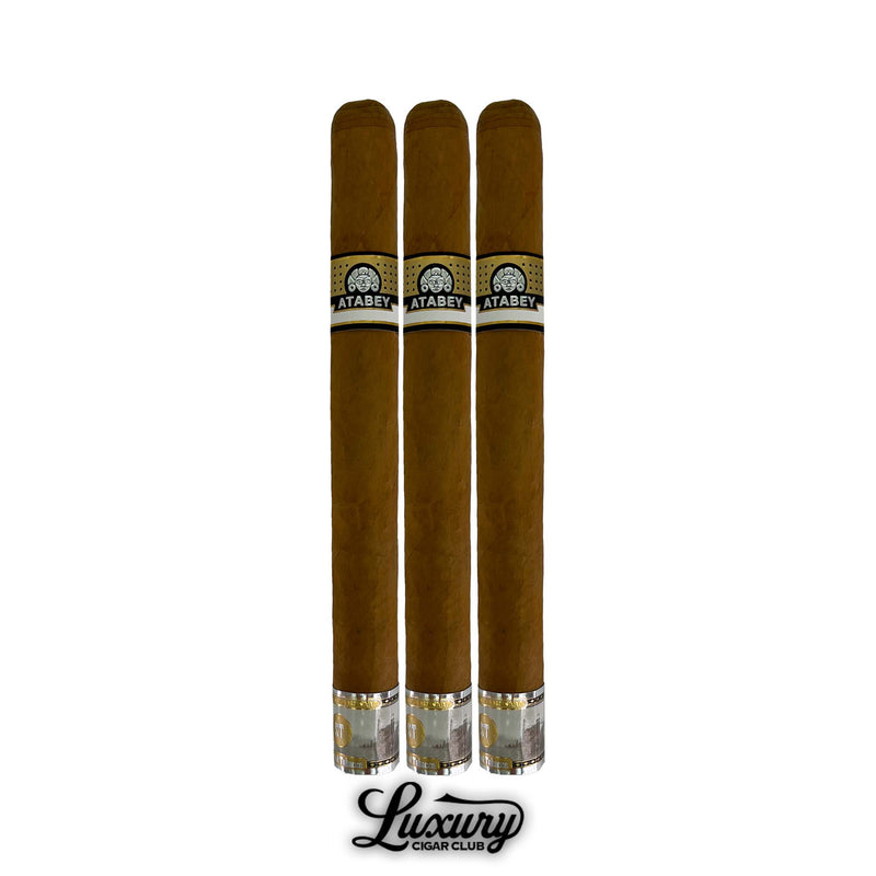 Three Atabey Dioses cigars with large format size, golden brown wrapper, classic Atabey black and gold bands, embossed golden foot rings, standing tall with Luxury Cigar Club branding below.