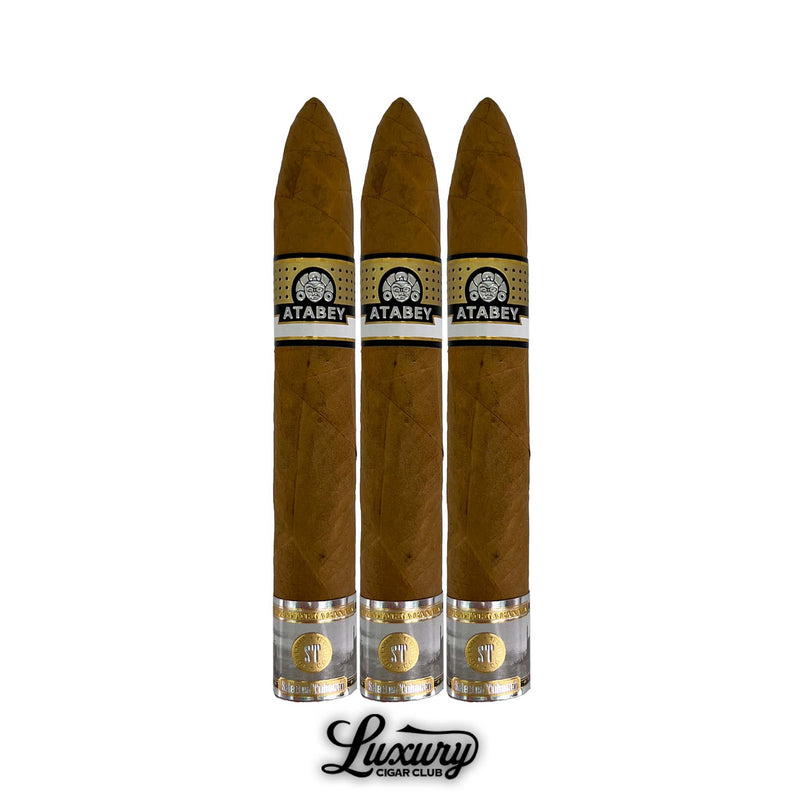 Three Atabey Duendes Torpedo cigars with pointed torpedo heads, light brown wrappers, black and gold Atabey bands, and metallic gold foot rings, displayed upright with Luxury Cigar Club logo at bottom.