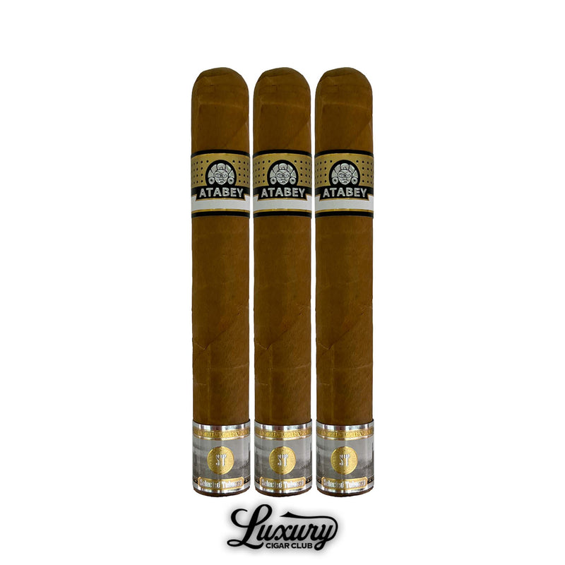 Trio of Atabey Ritos cigars with medium-long size, tan wrappers, gold and black Atabey logo bands, shiny golden foot details, arranged vertically with Luxury Cigar Club logo underneath.