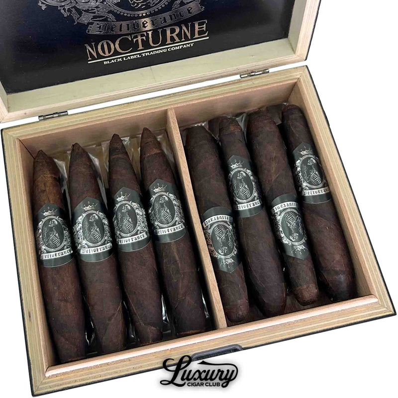 Luxury Cigar Club close-up shot of the Limited Edition Deliverance Nocturne combo box showing rows of dark, oily cigars with detailed silver skeleton crest bands neatly arranged inside a natural wood tray.