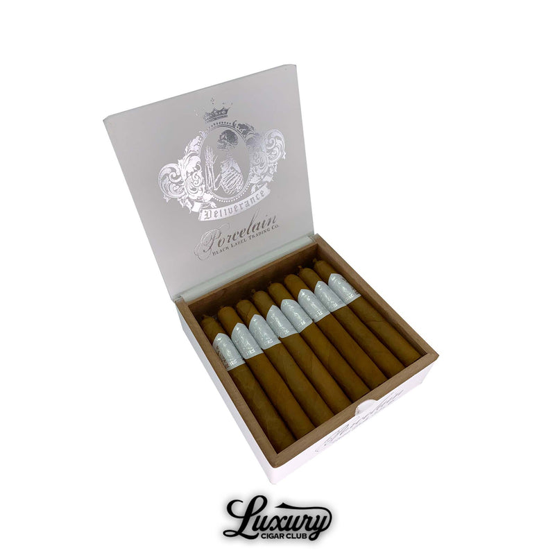 Black Label Trading Co. Deliverance Porcelain Corona Gordo cigars displayed in a white wooden box with silver embossed crest design, featuring smooth Connecticut wrappers and silver foil bands, presented by Luxury Cigar Club.