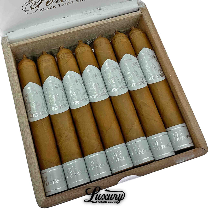 Close-up of Black Label Trading Co. Deliverance Porcelain Robusto cigars featuring smooth Connecticut wrappers and elegant silver foil bands inside a white wooden box, presented by Luxury Cigar Club.