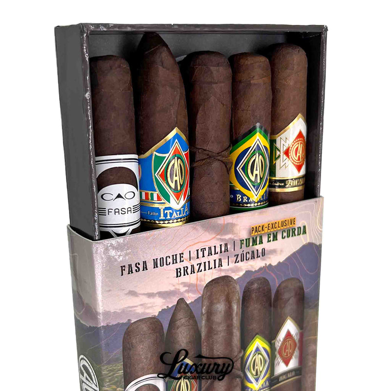 Close-up angled view of CAO Outpost Volume 2 sampler pack with five cigars partially lifted from the box, highlighting band designs from CAO FASA Noche, Italia, Brazilia, and Zocalo, Luxury Cigar Club.