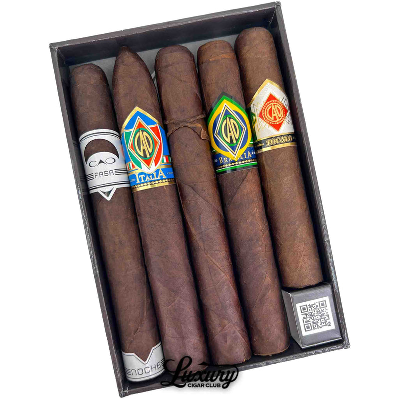 Open CAO Outpost Volume 2 sampler tray with five cigars laid inside, featuring CAO FASA Noche torpedo, CAO Italia, CAO Brazilia, and CAO Zocalo with visible band artwork, Luxury Cigar Club.