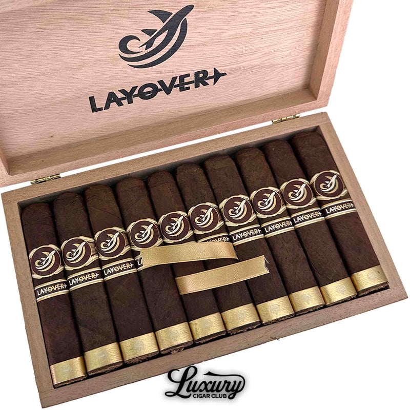 Close-up of Caldwell Lost & Found The Layover cigars highlighting their elegant gold ribbon and embossed logo inside the open box, featured by Luxury Cigar Club.