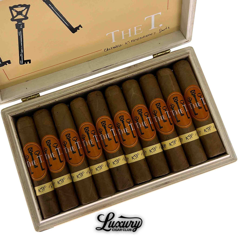 Close-up view of Caldwell The T Connecticut Robusto Minor cigars in a box, showing orange and gold cigar bands with key design, Luxury Cigar Club logo