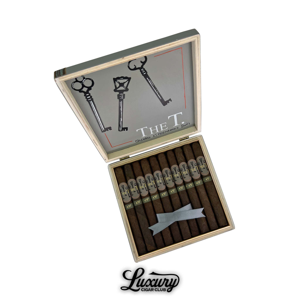Open box of Caldwell The T Lonsdale cigars by AJ Fernandez, Robert Caldwell, and Matt Booth, featuring dark brown wrappers and key-themed bands.