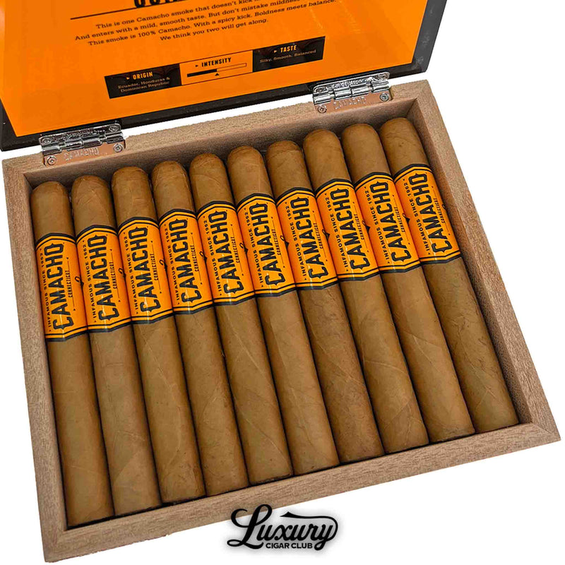 Close-up view of Camacho Connecticut Toro cigars in a wooden box, showcasing golden-brown Connecticut wrappers and bright orange Camacho bands. Luxury Cigar Club logo visible.