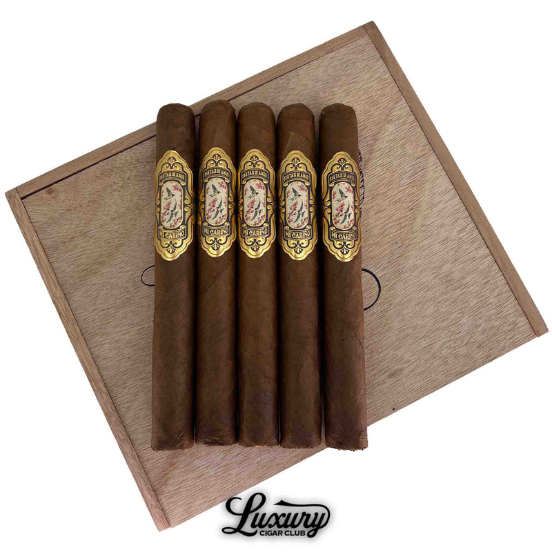 Close-up of Cartas de Amor Mi Cariño Corona Gorda cigars highlighting intricate gold and floral detailing on each band, presented by Luxury Cigar Club.