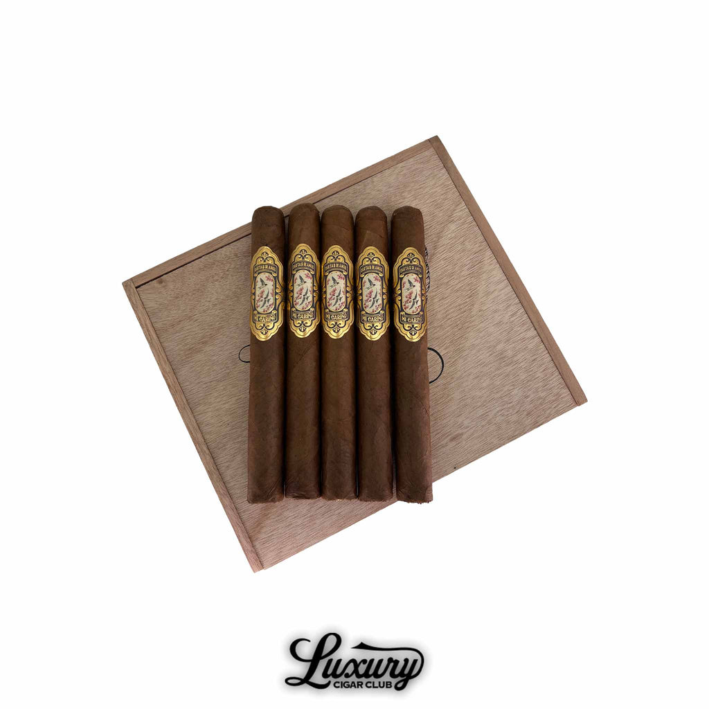 Cartas de Amor Mi Cariño Corona Gorda 5-pack cigars arranged on a wooden box lid, featuring ornate gold and floral bands, available at Luxury Cigar Club.