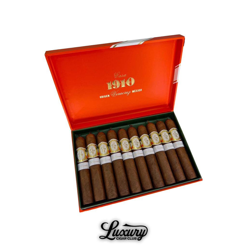 Open orange box of Casa 1910 Soldadera Edition La Coronela cigars from Veracruz Mexico showcasing ten cigars with golden embossed bands and white secondary labels. Luxury Cigar Club branding below.