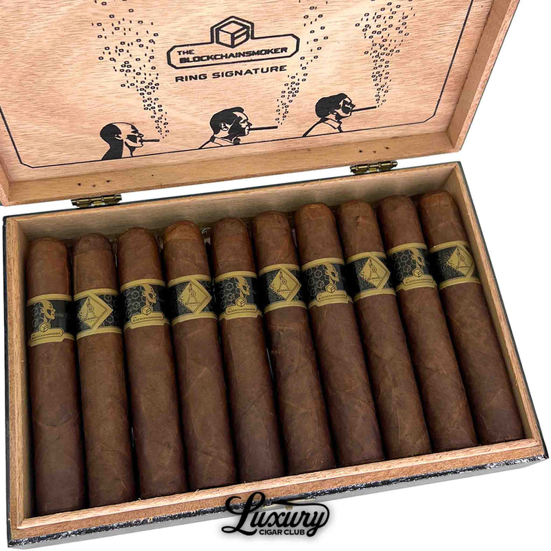 Close-up view of Casdagli The Blockchain Smokers Wide Churchill cigars from Luxury Cigar Club inside a wooden box, showing uniform reddish-brown wrappers, black-and-gold hexagonal cigar bands, and the illustrated lid with ring-signature graphics.