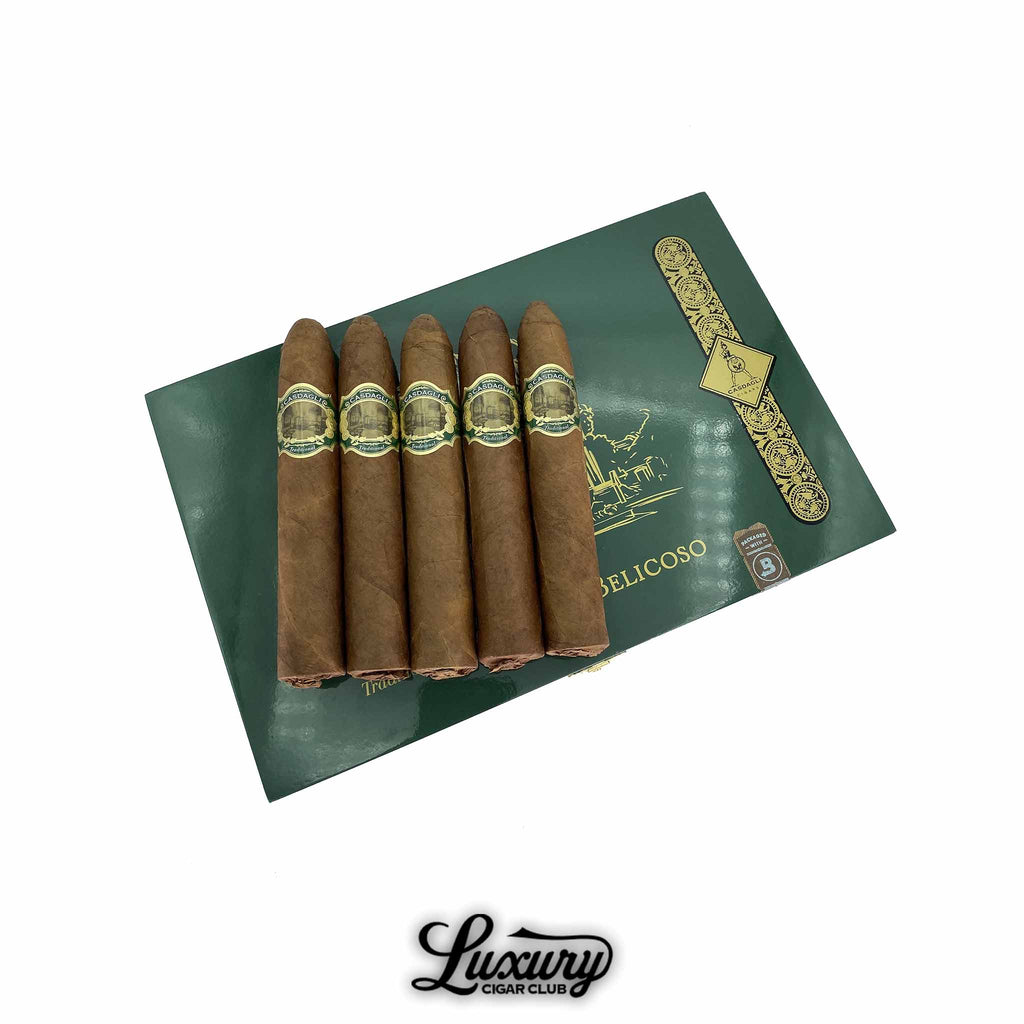 Five Casdagli Traditional Line Super Belicoso cigars from Luxury Cigar Club displayed on a green box lid with gold accents, showing their pointed figurado shape and elegant gold-and-green cigar bands.