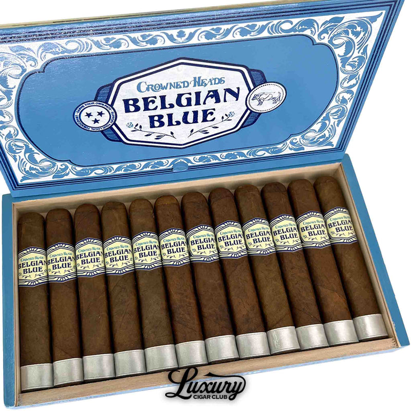 Close-up of Crowned Heads Belgian Blue Limited Edition 2025 Double Robusto BP cigars inside the open box, highlighting the uniform brown wrappers, cream-and-blue primary bands, and metallic silver foot bands. Decorative blue box lid with Belgian Blue branding visible. Luxury Cigar Club watermark at the bottom.