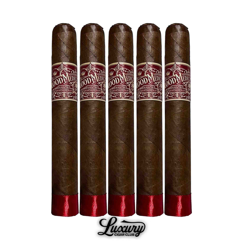 Five Crowned Heads Blood Medicine B Positive Limited Edition cigars standing upright, each wrapped in dark brown tobacco leaves with red and gold bands, finished with red foot ribbon, and the Luxury Cigar Club logo beneath.