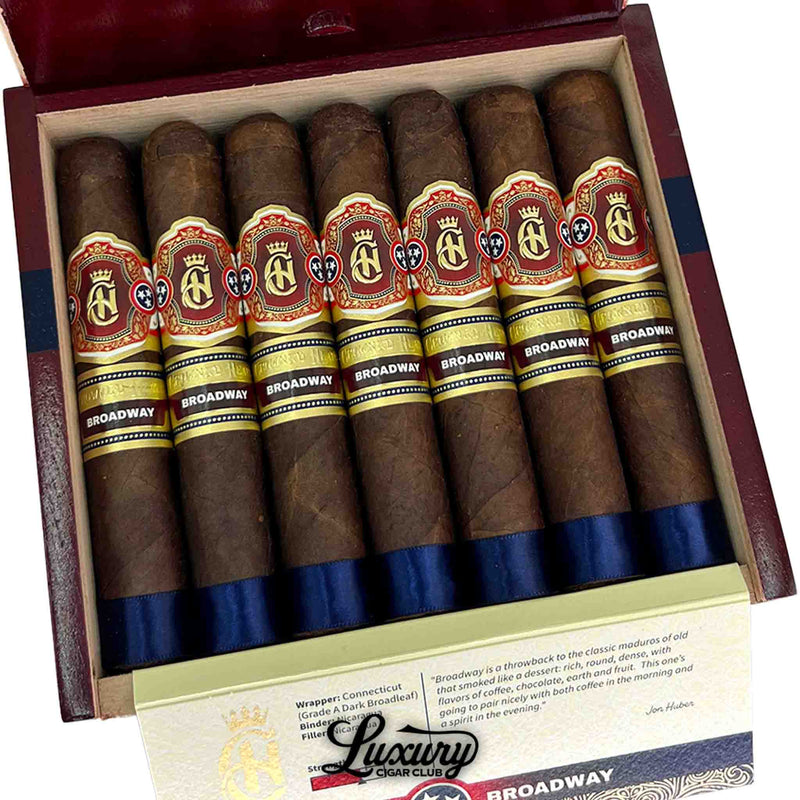 Close up view of Crowned Heads Broadway Epicure cigars with red and gold band and dark broadleaf wrapper at Luxury Cigar Club.