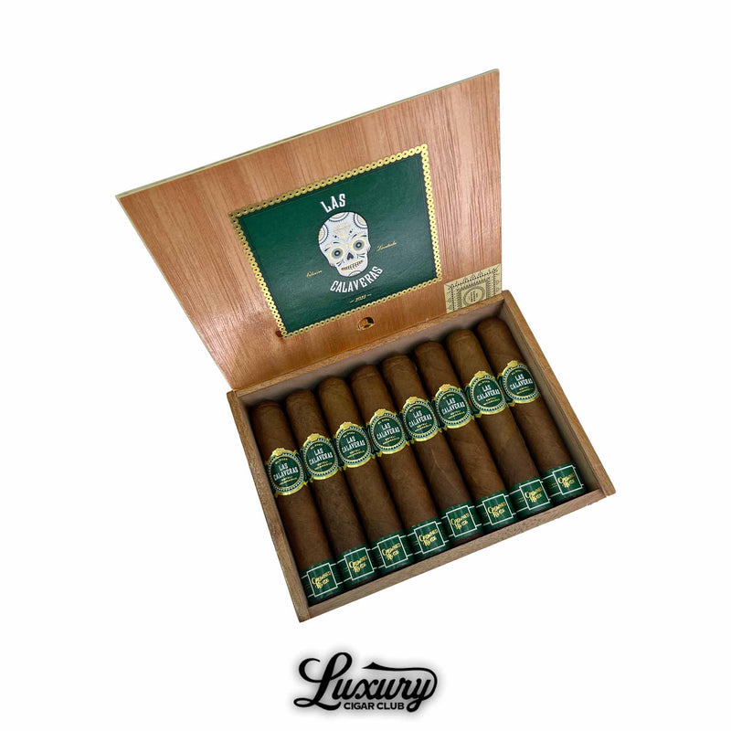Open wooden box of Crowned Heads Las Calaveras 2025 Limited Edition cigars with green and gold bands, featuring the signature skull logo inside the lid, displayed by Luxury Cigar Club.