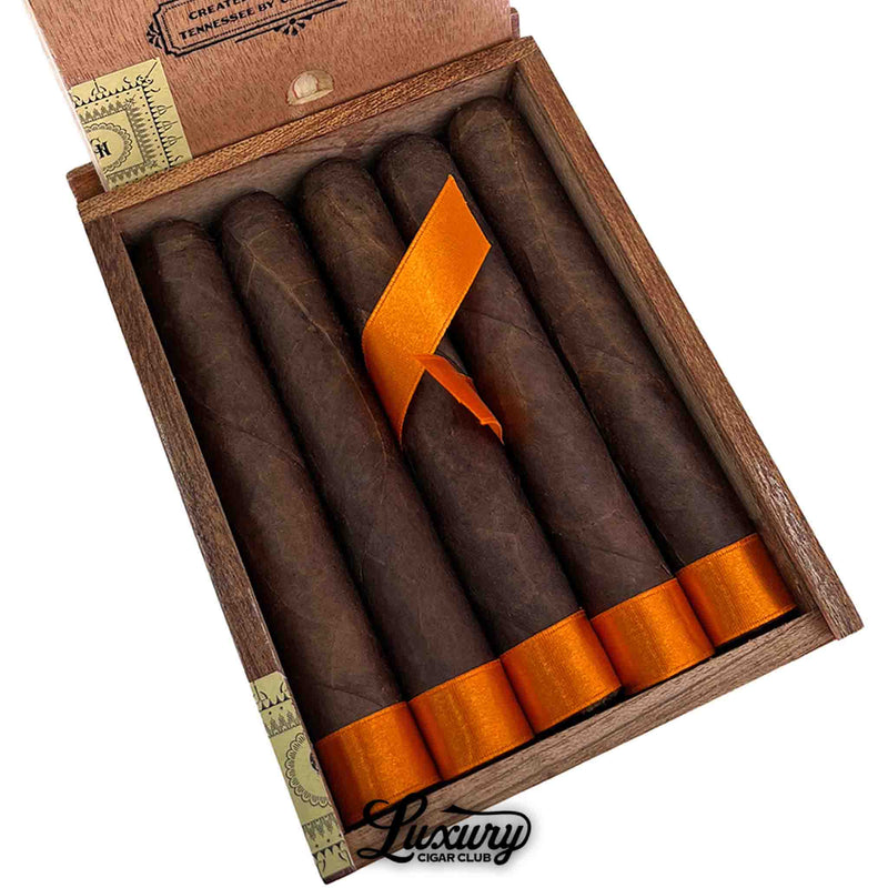 Close up detail of Crowned Heads Tennessee Waltz Robusto Extra Maduro cigars in open wooden box showing rich dark brown wrapper leaf and bright orange ribbon foot bands, Luxury Cigar Club branding
