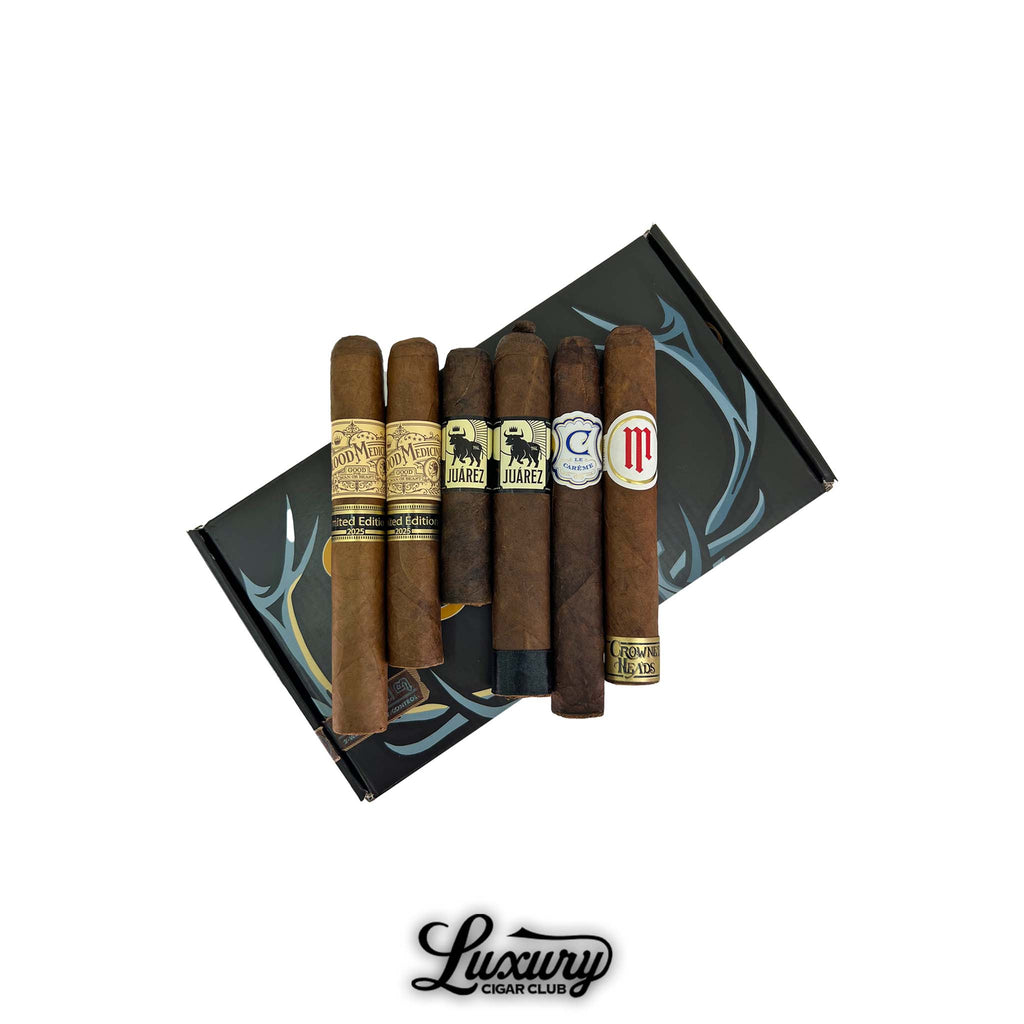 Crowned Heads The Regal Bloodline Sampler arranged over a branded black box with antler motif, featuring six cigars with varied bands and wrappers.