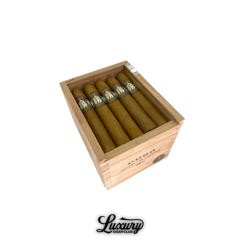 Open wooden crate of Dapper Cubo Claro Robusto cigars, showcasing neatly arranged golden-brown Connecticut-wrapped cigars with elegant blue, gold, and white bands featuring the Cubo emblem. The natural wood box highlights the brand’s classic design and craftsmanship, displayed above the Luxury Cigar Club logo. Luxury Cigar Club.