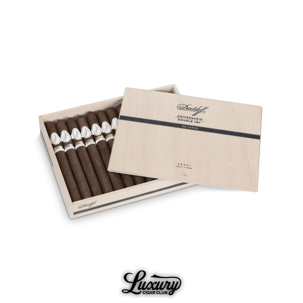 Open light-wood box of Davidoff 702 Series Aniversario Double “R” cigars, featuring ten dark-brown, robusto-gauge sticks and a matching sliding lid printed “Aniversario Double «R» 702 Series"