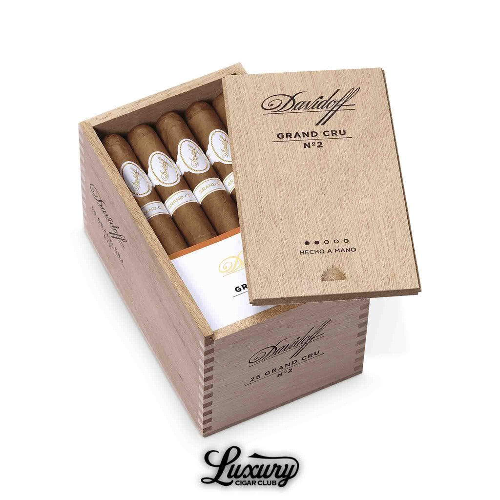 Open cedar box of Davidoff Grand Cru No. 2 cigars, partially covered by a sliding wooden lid engraved with the Davidoff logo, showing neatly arranged cigars with white and gold bands, and “Luxury Cigar Club” logo at the bottom.