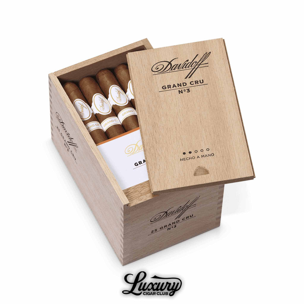 Wooden Davidoff Grand Cru No. 3 box partially opened, filled with hand-crafted cigars featuring white and gold Grand Cru bands, engraved lid branding, shown with Luxury Cigar Club logo.