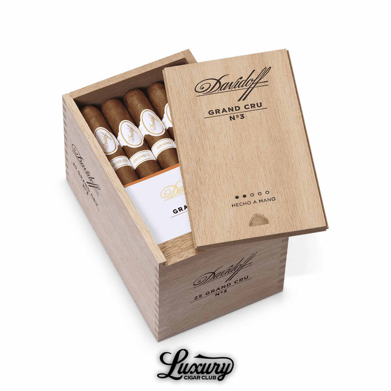 Wooden Davidoff Grand Cru No. 3 box partially opened, filled with hand-crafted cigars featuring white and gold Grand Cru bands, engraved lid branding, shown with Luxury Cigar Club logo.