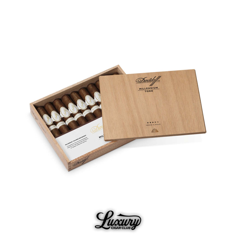 Open box of Davidoff Millennium Toro cigars with smooth brown wrappers and white bands, partially covered by a wooden lid.