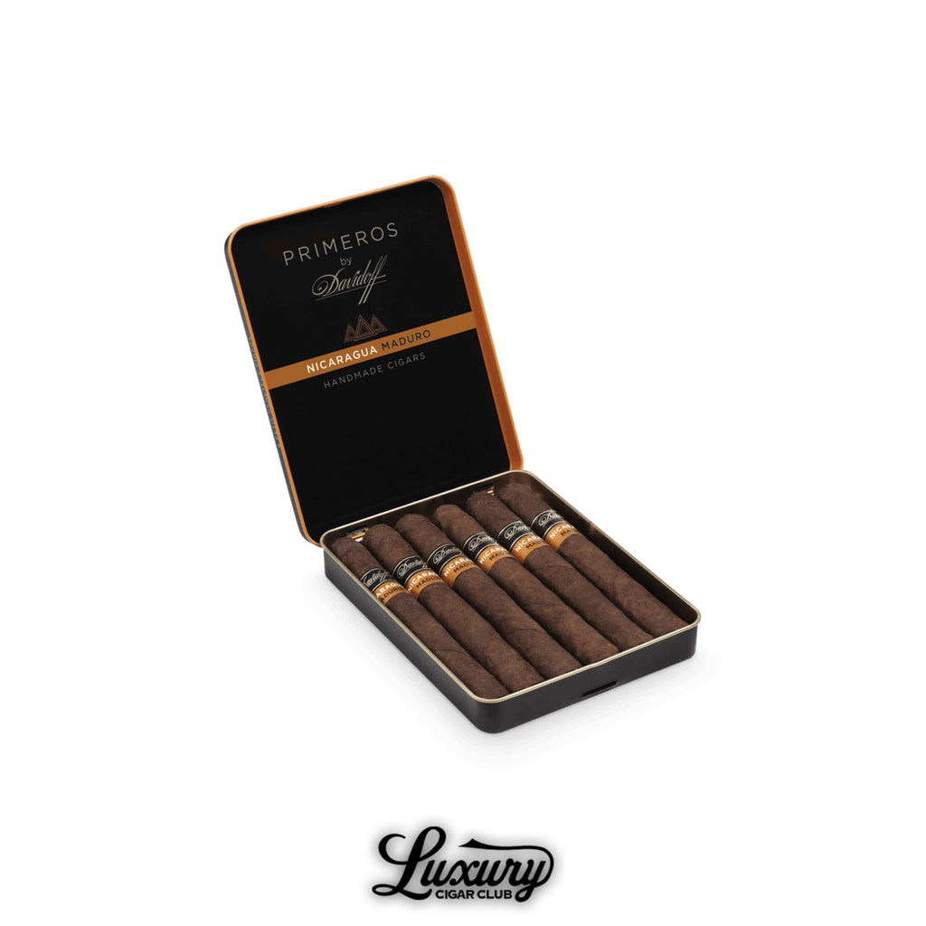 Open tin of Davidoff Primeros Nicaragua Maduro Petit Panatela cigars, featuring dark brown wrappers and black bands with orange accents, set against a white background with Luxury Cigar Club branding.