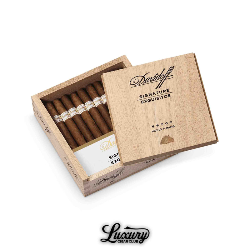 Open cedar box of Davidoff Signature Exquisitos cigars, showing neatly arranged small-format cigars with white and gold bands, partially covered by a sliding wooden lid engraved with Davidoff Signature Exquisitos, and the Luxury Cigar Club logo below.