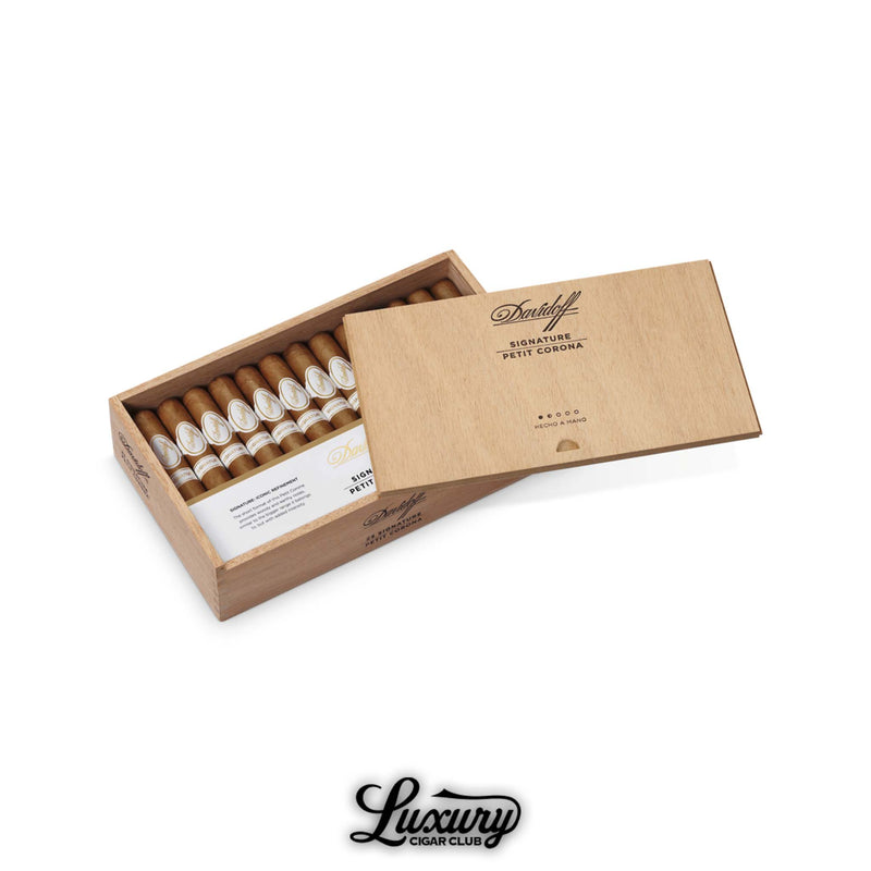 Box of Davidoff Signature Petit Corona cigars in natural wooden case, open to reveal hand-rolled cigars with refined white and gold bands, lid engraved with cigar details, Luxury Cigar Club logo displayed below.