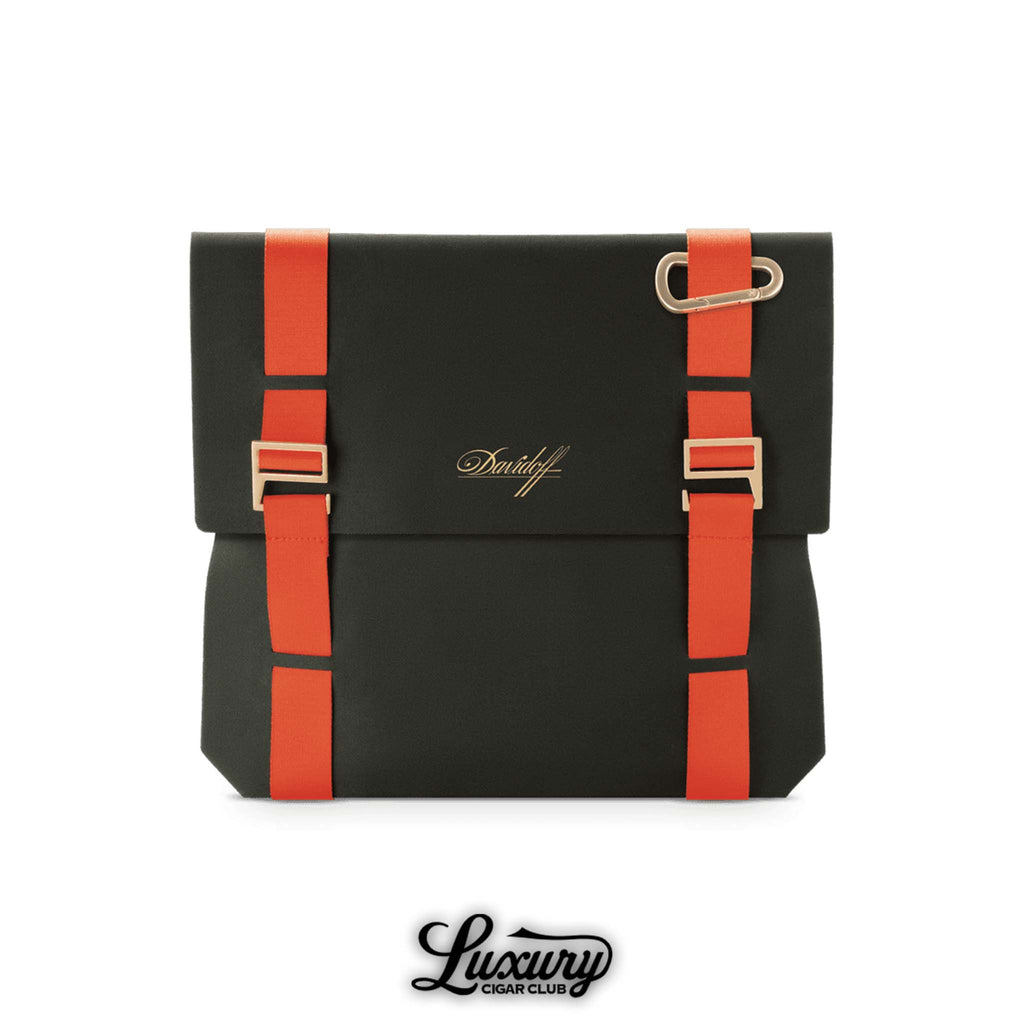 Davidoff Travel Humidor Explorer in sleek black with vibrant orange straps and gold hardware, featuring the elegant Davidoff logo embossed in gold across the front. The modern, water-resistant design offers secure storage for cigars while traveling in style. Displayed above the Luxury Cigar Club logo. Luxury Cigar Club.